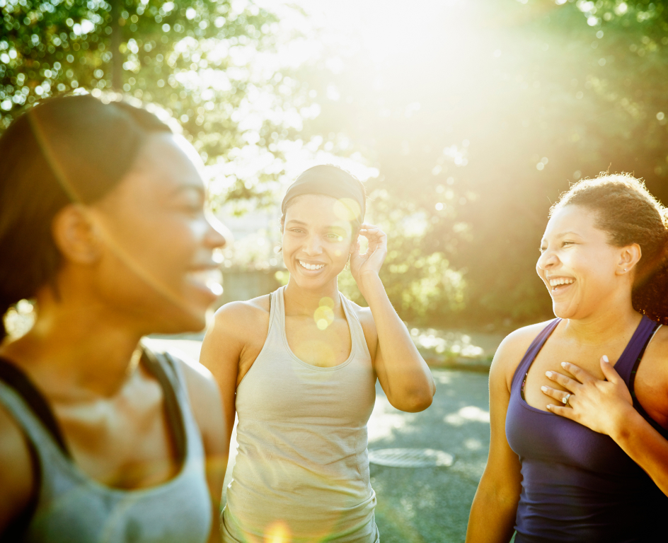 Three women in activewear smiling outside