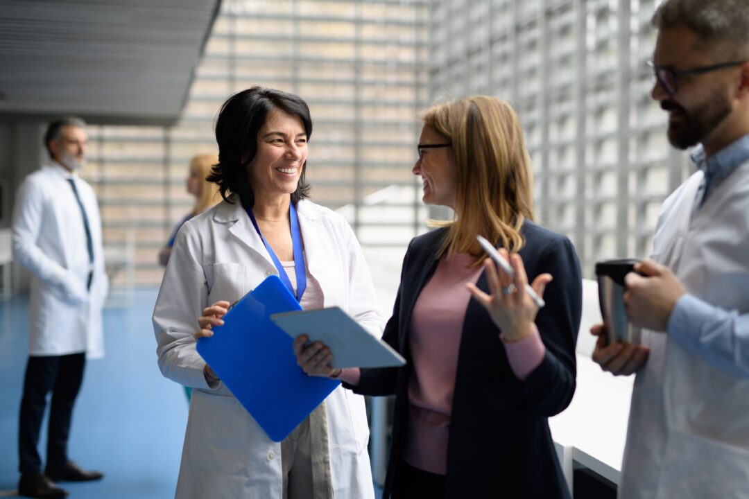 Doctors talking to pharmaceutical sales representative, presenting new pharmaceutical product. Hospital director, manager talking with doctors team.